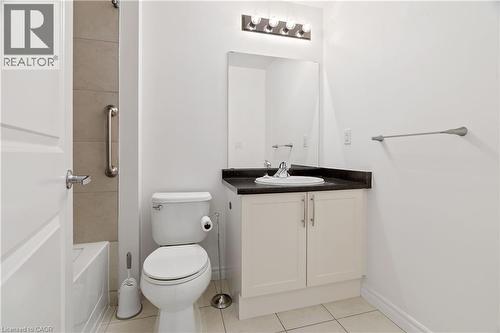 Bathroom featuring a white vanity with a dark countertop, an undermount sink, and a mirrored medicine cabinet with a four-bulb light fixture - 427 Aberdeen Avenue Unit# 102, Hamilton, ON - Indoor Photo Showing Bathroom