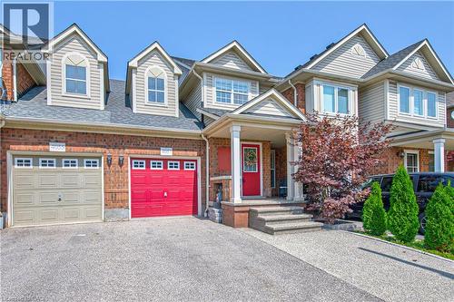Brick and siding exterior featuring gabled dormers, a covered porch with white columns, and a bright red entry door - 4057 Donnic Drive, Burlington, ON - Outdoor With Facade