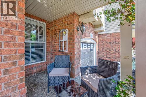 Covered exterior entryway featuring brick and siding construction, a single window with white blinds, and a built-in overhead light fixture - 4057 Donnic Drive, Burlington, ON - Outdoor With Deck Patio Veranda With Exterior