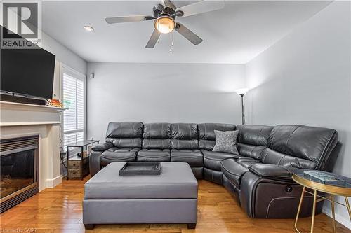 Living area featuring wood-finish flooring, a white mantel, and a ceiling fan with integrated lighting - 4057 Donnic Drive, Burlington, ON - Indoor Photo Showing Living Room With Fireplace
