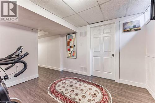 Finished basement area featuring wood-finish flooring, white walls, and a white paneled door - 4057 Donnic Drive, Burlington, ON - Indoor Photo Showing Other Room