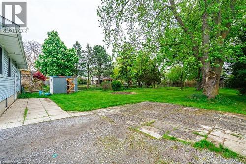 Expansive rear yard featuring a gravel driveway, concrete patio, detached storage shed, mature trees, and a substantial lawn area - 2583 Binbrook Road, Binbrook, ON - Outdoor