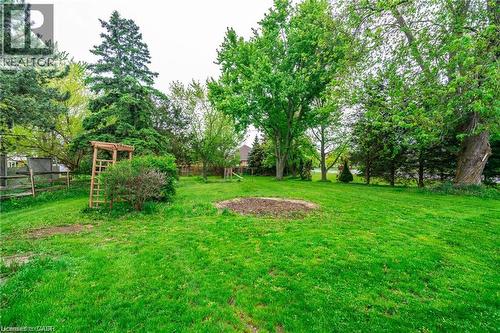 Expansive green lawn with mature trees and a wooden garden trellis - 2583 Binbrook Road, Binbrook, ON - Outdoor