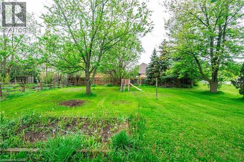 Expansive green lawn with mature trees and a partial wood fence - 2583 Binbrook Road, Binbrook, ON - Outdoor