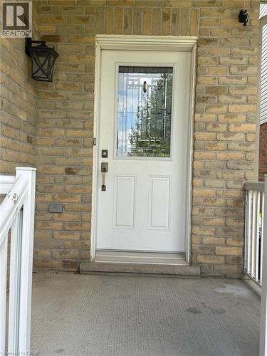 Front entry featuring a white door with decorative glass inserts, brick exterior, concrete porch, and white railings - Upper-313 Featherstone Crescent, Kitchener, ON - Outdoor With Exterior