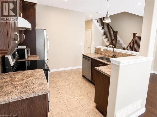 Kitchen featuring dark wood-finish cabinetry, stainless steel appliances, and stone-look countertops - Upper-313 Featherstone Crescent, Kitchener, ON - Indoor Photo Showing Kitchen With Double Sink