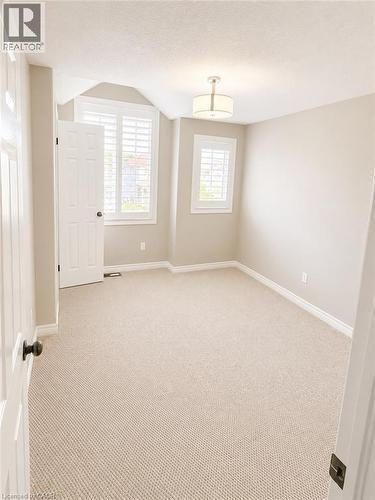 Carpeted room with neutral paint, featuring two windows with white plantation shutters, white trim, and a semi-flush mount ceiling light - Upper-313 Featherstone Crescent, Kitchener, ON - Indoor Photo Showing Other Room