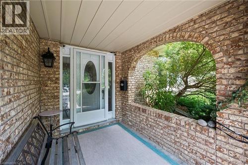Covered brick entry porch featuring an arched opening, a white front door with oval glass insert and sidelights, an overhead light fixture, and brick exterior walls - 8 Perin Place, Kitchener, ON - Outdoor