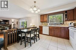 Kitchen featuring wood cabinetry, light-toned countertops, a mosaic tile backsplash, and a large window above the sink - 