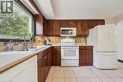Kitchen featuring wood cabinetry, light-toned countertops, and a mosaic tile backsplash - 
