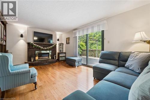 Hardwood-finish flooring throughout, brick fireplace with a metallic insert, and sliding glass doors opening to an outdoor deck - 8 Perin Place, Kitchener, ON - Indoor Photo Showing Living Room With Fireplace