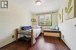 Bedroom featuring rich wood-finish flooring and a single window with blinds - 