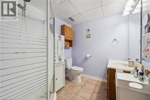 Three-piece bathroom featuring a shower with frosted glass enclosure, a single vanity with wood cabinetry, and neutral-toned floor tiling - 8 Perin Place, Kitchener, ON - Indoor Photo Showing Bathroom