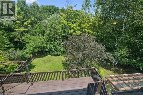 Expansive outdoor deck with wood-finish flooring and railing, overlooking a fenced grassy yard - 8 Perin Place, Kitchener, ON - Outdoor