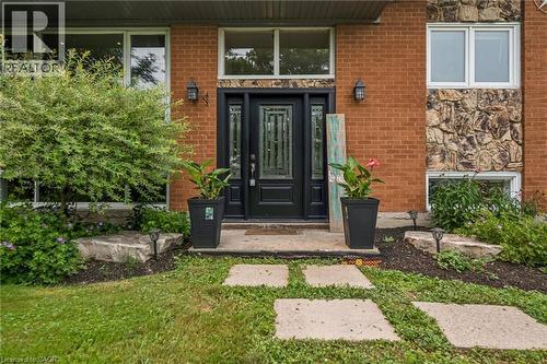 Brick exterior featuring a stone accent wall, an ornate black entry door with sidelights, and a transom window - 7988 Wellington Road 12, Arthur, ON - Outdoor