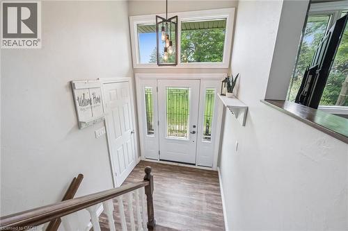 Two-story foyer featuring a prominent front entry door with sidelights, transom windows, wood-finish flooring, and a contemporary chandelier - 7988 Wellington Road 12, Arthur, ON - Indoor Photo Showing Other Room