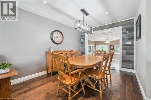 Dining area featuring wood-finish flooring, a contemporary linear chandelier, recessed lighting, and a decorative paneled accent wall - 7988 Wellington Road 12, Arthur, ON - Indoor Photo Showing Dining Room