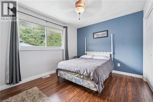 Room featuring wood-finish flooring, a prominent window, a ceiling fan, and a blue accent wall - 7988 Wellington Road 12, Arthur, ON - Indoor Photo Showing Bedroom