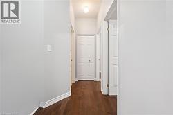 Hallway featuring wood-finish flooring, light gray walls, white trim, and recessed lighting - 