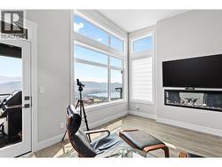 Bright and spacious living room featuring a cozy fireplace and oversized windows showcasing spectacular lake views. - 
