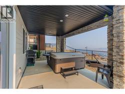 Covered lower patio, currently set up for a hot tub, offering a relaxing outdoor retreat with beautiful lake views. - 