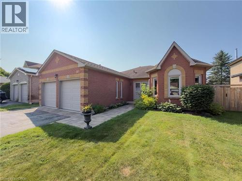 Brick exterior home featuring a two-car garage, bay window, front landscaping, paved walkway, and a manicured lawn - 60 Attwood Drive, Cambridge, ON - Outdoor