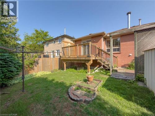 Elevated wood deck with stairs, red brick exterior, and a spacious backyard featuring a garden bed - 60 Attwood Drive, Cambridge, ON - Outdoor