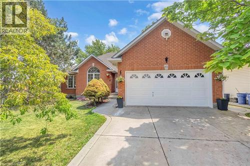 Brick exterior featuring an integrated two-car garage with arched window inserts, a concrete driveway, and a front walkway - 65 Thistlemoor Drive, Caledonia, ON - Outdoor