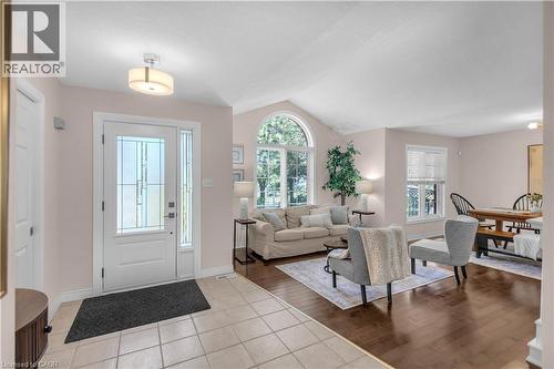 Entryway featuring a white door with decorative glass inserts and a sidelight, ceramic tile flooring, and a contemporary semi-flush mount light fixture - 65 Thistlemoor Drive, Caledonia, ON - Indoor