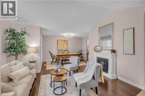 Living area featuring wood-finish flooring, a white mantel fireplace, and vaulted ceilings - 65 Thistlemoor Drive, Caledonia, ON - Indoor Photo Showing Living Room With Fireplace