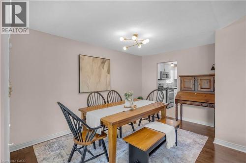 Dining area with a modern sputnik-style chandelier and warm wood-finish flooring - 65 Thistlemoor Drive, Caledonia, ON - Indoor Photo Showing Dining Room