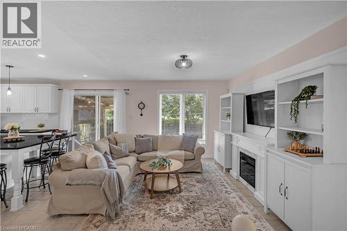 Open-concept living space featuring a built-in entertainment center with an electric fireplace, white cabinetry, and recessed lighting - 65 Thistlemoor Drive, Caledonia, ON - Indoor Photo Showing Living Room With Fireplace