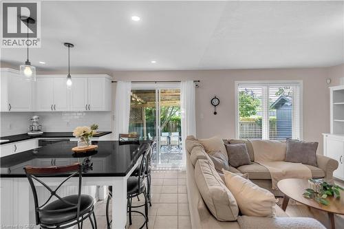 Open-concept kitchen and living area featuring a large kitchen island with seating, white cabinetry, black countertops, and a subway tile backsplash - 65 Thistlemoor Drive, Caledonia, ON - Indoor Photo Showing Living Room