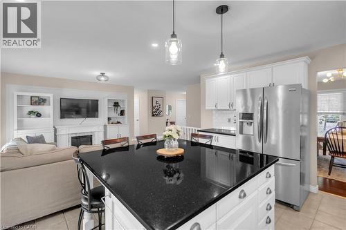 Kitchen island featuring a black countertop, white base cabinetry, and pendant lighting - 65 Thistlemoor Drive, Caledonia, ON - Indoor Photo Showing Kitchen With Upgraded Kitchen
