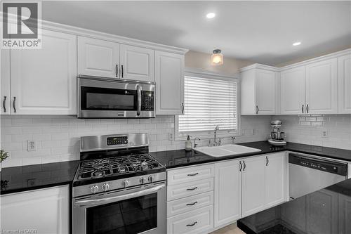 Kitchen featuring white shaker-style cabinetry, dark countertops, a stainless steel range, a stainless steel over-the-range microwave, and a white subway tile backsplash - 65 Thistlemoor Drive, Caledonia, ON - Indoor Photo Showing Kitchen With Upgraded Kitchen