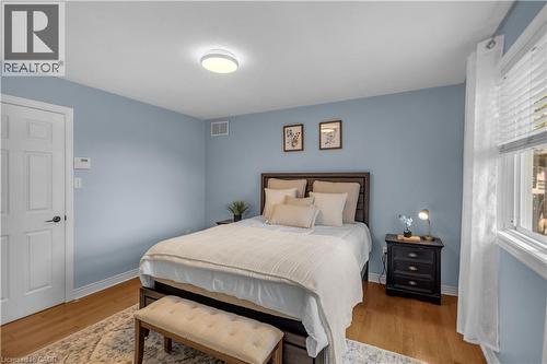 Bedroom featuring hardwood flooring, a multi-pane window, a white paneled door, and a flush-mount ceiling light fixture - 65 Thistlemoor Drive, Caledonia, ON - Indoor Photo Showing Bedroom