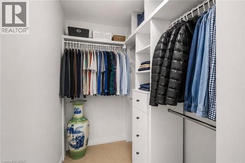 Walk-in closet featuring built-in shelving, multiple hanging rods, and integrated drawer storage - 65 Thistlemoor Drive, Caledonia, ON - Indoor With Storage