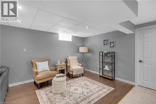 Finished room featuring wood-finish flooring, a drop ceiling with recessed lighting, painted walls, and a white interior door with black hardware - 65 Thistlemoor Drive, Caledonia, ON - Indoor
