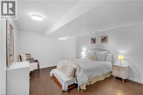 Spacious bedroom featuring wood-finish flooring, white baseboards, and a contemporary ceiling light fixture - 65 Thistlemoor Drive, Caledonia, ON - Indoor Photo Showing Bedroom