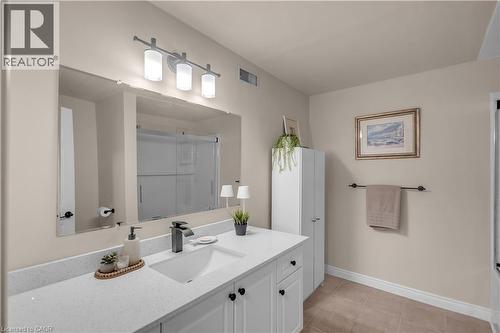 Bathroom featuring a large vanity with an integrated sink, a dark finish faucet, and a wall-mounted tri-light fixture - 65 Thistlemoor Drive, Caledonia, ON - Indoor Photo Showing Bathroom