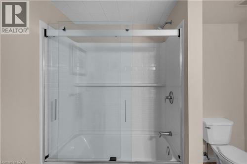 Bathtub and shower combination featuring clear glass sliding enclosure and white subway tile surround - 65 Thistlemoor Drive, Caledonia, ON - Indoor Photo Showing Bathroom