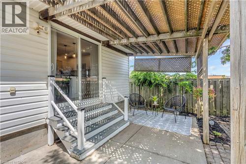 Private patio featuring a pergola, concrete hardscaping, and a wooden privacy fence - 65 Thistlemoor Drive, Caledonia, ON - Outdoor