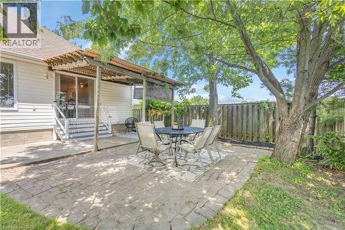 Outdoor patio featuring paver stone flooring, a wooden pergola, and mature trees providing natural shade - 65 Thistlemoor Drive, Caledonia, ON - Outdoor
