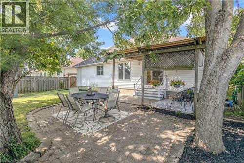 Expansive patio with stone paver surround, mature trees, and a wooden pergola structure - 65 Thistlemoor Drive, Caledonia, ON - Outdoor