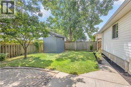 Expansive rear yard featuring a paved patio area, mature trees, manicured lawn, and a storage shed - 65 Thistlemoor Drive, Caledonia, ON - Outdoor