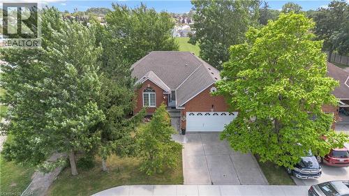 Brick exterior home featuring a gabled roof, a two-car garage, a concrete driveway, and established front yard trees - 65 Thistlemoor Drive, Caledonia, ON - Outdoor