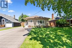 Ranch-style exterior with neutral siding, a front lawn, and a paved driveway - 