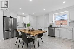 Bright kitchen featuring white shaker cabinetry, stainless steel appliances, white subway tile backsplash, and large format tile flooring - 