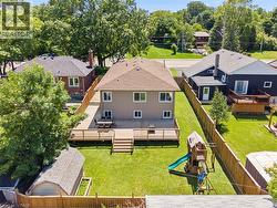 Spacious backyard featuring a large wood-finish deck with railings, a manicured lawn, full privacy fencing, and a detached storage shed - 