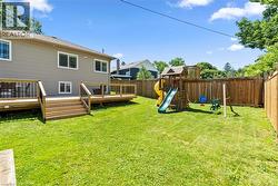 Expansive rear yard featuring a multi-level wood deck with stairs, a wooden privacy fence, and a green lawn - 